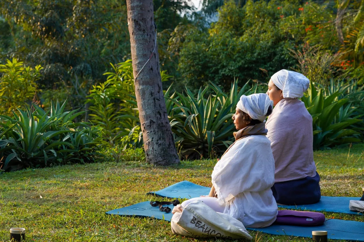 Two participants seated in meditation in a garden during the training